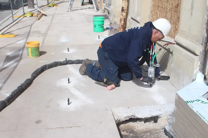 Crew injecting polyurethane foam to lift a commercial concrete slab on a job site